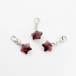 Detailed view of three deep red crystal star pendants with silver lobster clasps
