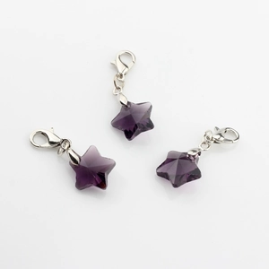 Close-up of three purple crystal star pendants with silver lobster clasps on white background