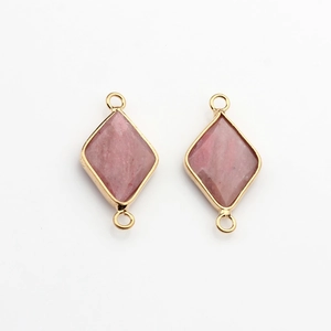 Macro view of pink natural stone rhombus charms with gold trim and dual connection rings