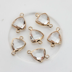 Detail of six faceted triangle crystal charms with gold-plated double-hole frames for DIY jewelry