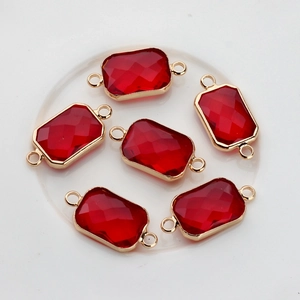 Close-up of six red rectangular faceted crystal charms with gold edges for jewelry making