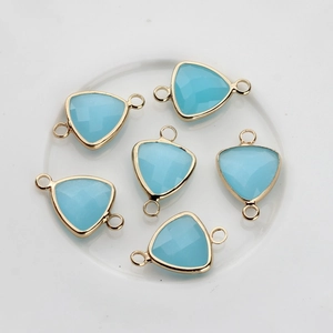 Macro detail of sky blue faceted triangle stone connectors with gold plated dual loops