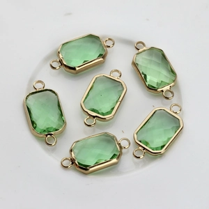 Macro shot of rectangular green faceted crystal connector with gold-plated copper edges