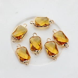 Macro shot of amber rectangular faceted crystal charms with gold-plated edges and dual loops