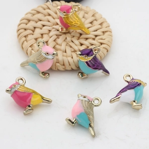 Macro detail of colorful enamel bird charms with gold plating for DIY jewelry making