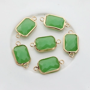 Macro shot of rectangular emerald faceted crystal charms with gold edges and dual rings
