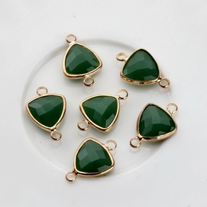 Detailed view of six gold-plated triangle crystal charms with green faceted stones