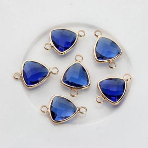 Macro detail of faceted blue crystal triangle charms with gold plated double rings