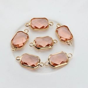 Macro shot of rectangular peach faceted crystal pendants with gold plated double rings