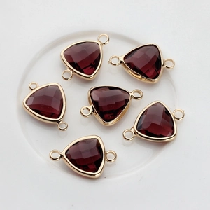 Macro detail of burgundy triangular crystal connectors in gold-plated copper frames