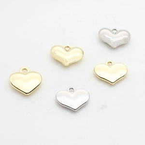 Primer plano de dijes de corazón en oro y plata para la creación de joyas DIY