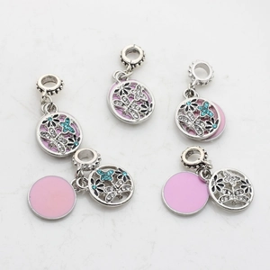 Dettaglio di ciondoli a farfalla e fiori in argento con smalto rosa e strass blu