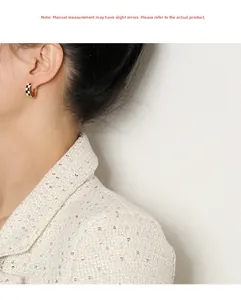 Détail des boucles d'oreilles en émail à damier portées pour référence de taille réelle
