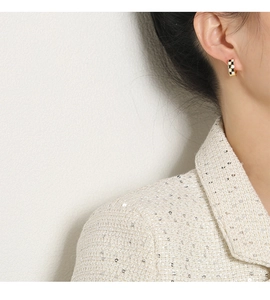 Vue rapprochée des boucles d'oreilles créoles à damier noir et blanc sur modèle