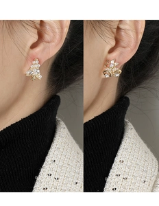 Detalle de pendientes de clip asimétricos con árbol de Navidad y cascabeles