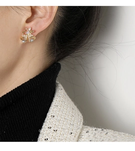Detalle de pendientes de clip navideños con lazo dorado y cristales en la modelo