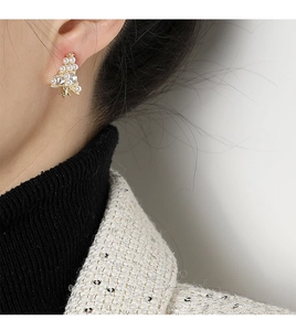 Detalle de pendientes de clip de árbol de Navidad con perlas blancas y pedrería brillante