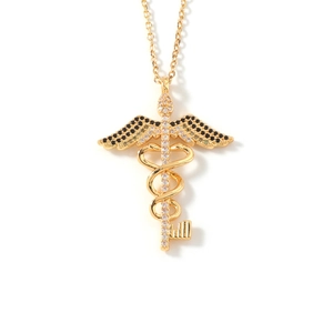Detail shot of golden medical caduceus pendant necklace with black and white rhinestones