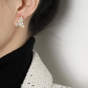 Pendientes asimétricos de árbol de Navidad con perlas y cristales en una modelo