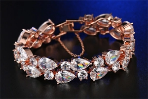 Macro detail of rose gold bracelet featuring pear-cut cubic zirconia and secure safety chain