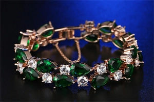 Detail of rose gold bracelet with pear-cut green zircon and safety chain attachment