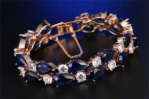 Detailed close-up of rose gold bracelet with pear-cut blue crystals and a secure safety chain