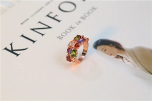 Détail de bague en or rose sertie de pierres précieuses multicolores en taille poire