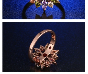Makro-Detail des Roségold-Blütenrings mit bunten Kristallen auf blauem Hintergrund
