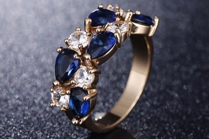 Vue macro d'une bague en or rose avec cristaux bleus en goutte et détails en zircone
