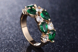 Gros plan de cristaux verts en goutte et zircons ronds sur une bague en or rose