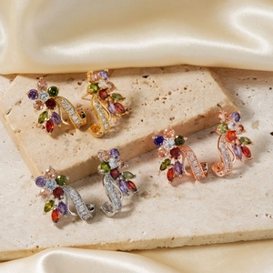 Detailed macro view of 18K gold-plated earrings with colorful zircon stones on stone tray