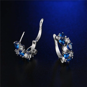 Dettaglio degli orecchini a cerchio in argento con zirconi blu e bianchi a forma di pera