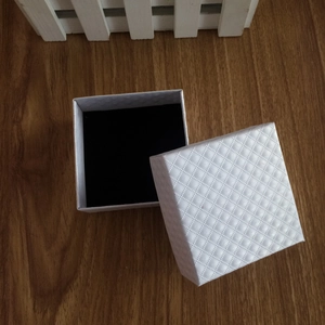 Detailopname van een witte juwelendoos met ruittextuur en een zwarte fluwelen voering