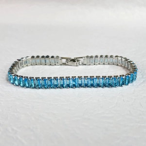 Macro view of blue rectangular zircon stones set in a gunmetal finish tennis bracelet