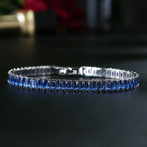 Macro shot of silver tennis bracelet featuring dark blue baguette-cut cubic zirconia stones