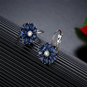 Makroaufnahme von dunkelblauen Blumen-Creolen mit polierten silbernen Metallblüten