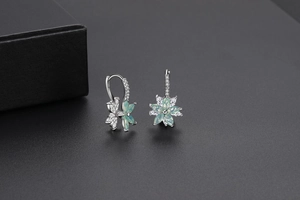 Détail de boucles d'oreilles fleurs avec opale vert pâle et pierres de zircon blanc