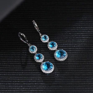 Detail of three-tier drop earrings with round blue gemstones and sparkling diamond halos