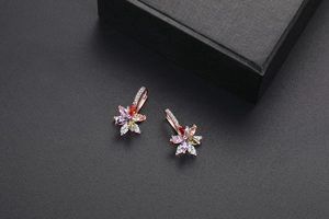 Détail macro de boucles d'oreilles fleurs doubles avec zircons colorés et base en or rose