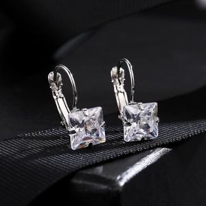 Macro shot of silver zircon earrings with princess cut crystals on black gift ribbon