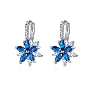 Gros plan de boucles d'oreilles créoles fleurs argentées avec pierres bleues et blanches