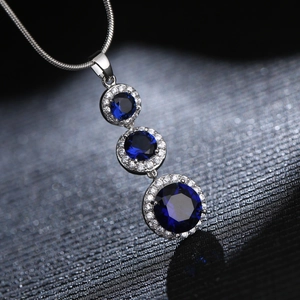 Minimalist silver necklace featuring three tiered blue crystals with halo pavé setting