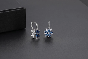 Détail de boucles d'oreilles fleur à deux couches avec pierres bleues et plaquage argent