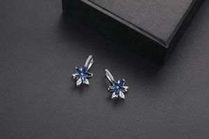 Détail macro de boucles d'oreilles fleur en argent avec zircons bleu foncé et cristaux blancs