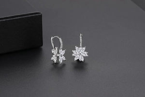 Gros plan de boucles d'oreilles fleur en argent avec zircons sur une surface grise