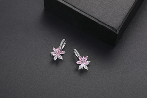 Détail de boucles d'oreilles fleur en argent avec zircons roses sur cuir noir