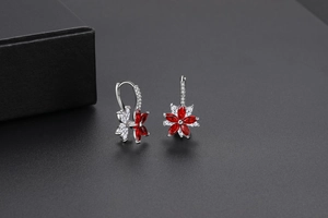 Détail des boucles d'oreilles fleur en argent avec pierres rouges et zircons brillants