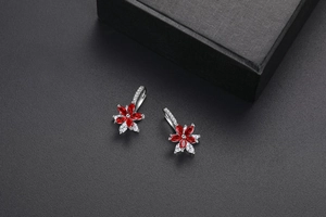 Détail d'une boucle d'oreille fleur double couche avec pierres marquises rouges et zircon