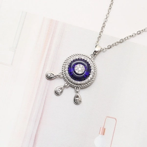 Silver Evil Eye necklace with blue glass stone and teardrop pendants on magazine page