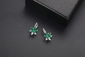 Détail macro de boucles d'oreilles fleur en zircon vert émeraude sur fond noir